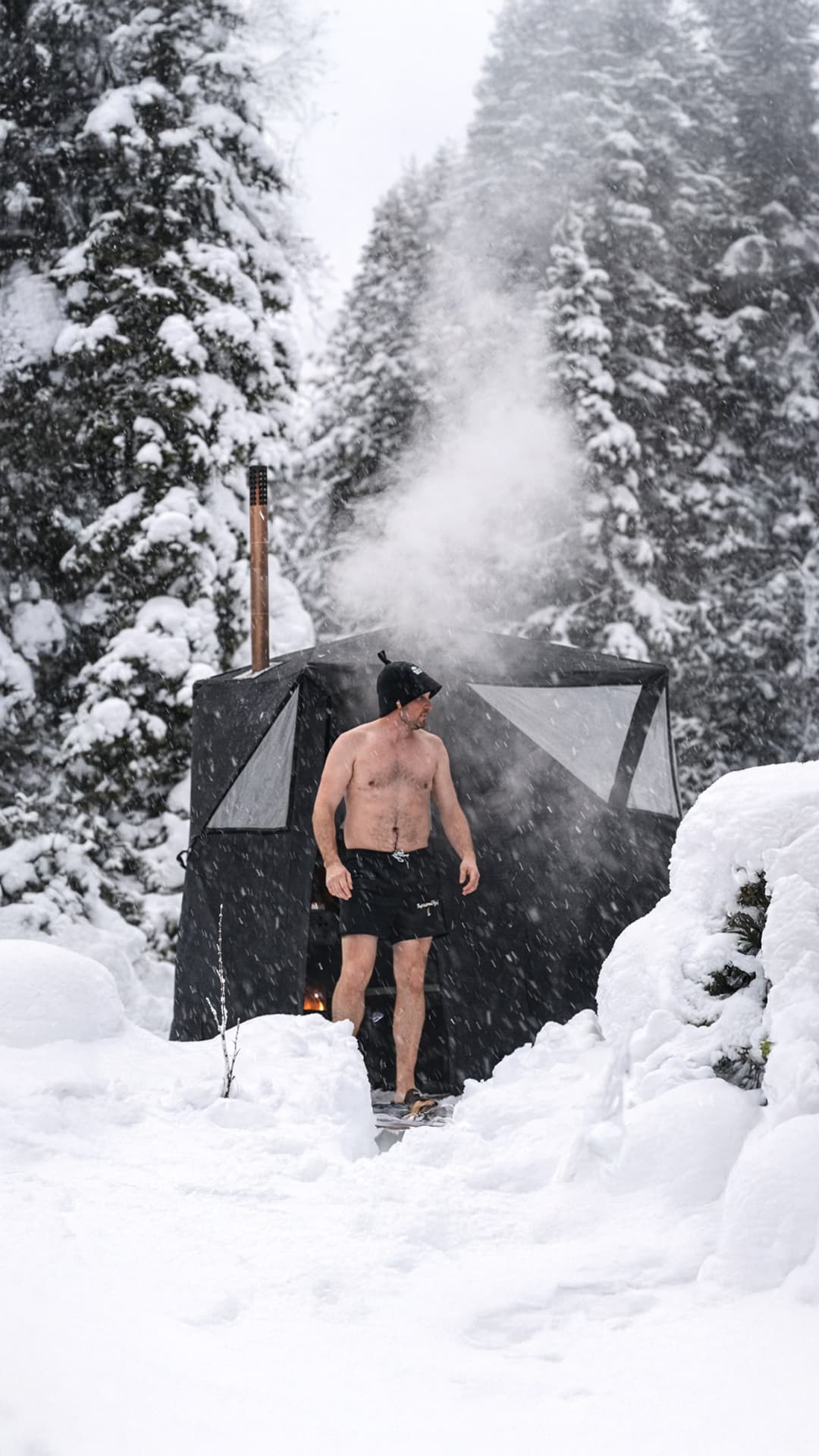A bather stepping out of the Näver into heavy falling snow with steam rising from the chimney