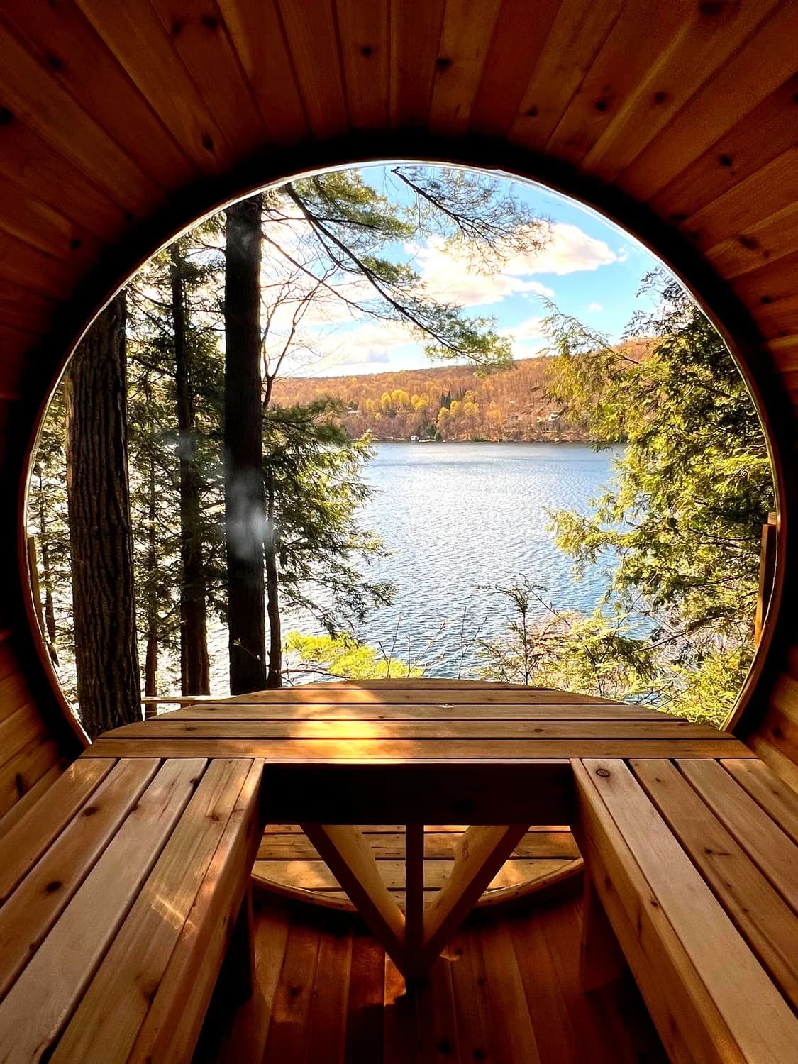 Interior of a SaunaSpa.ca barrel sauna looking out through a large panoramic window over a lake