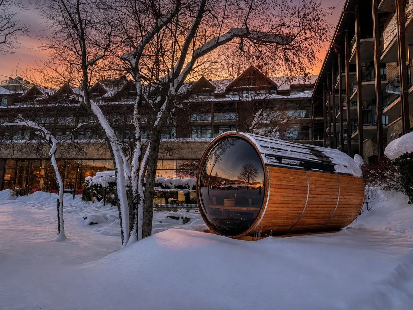 SaunaSpa.ca barrel sauna in deep snow outside a condo building at dusk
