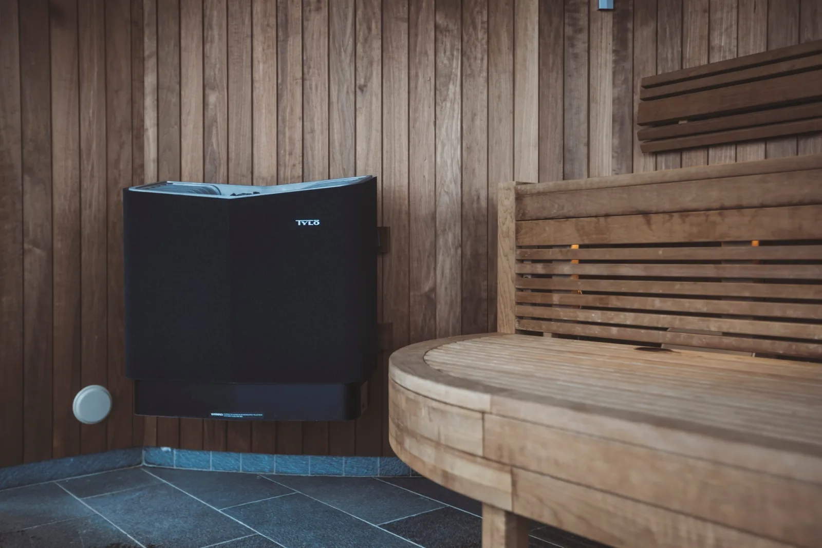 Tylö heater installed in a modern home sauna with stone-faced wall